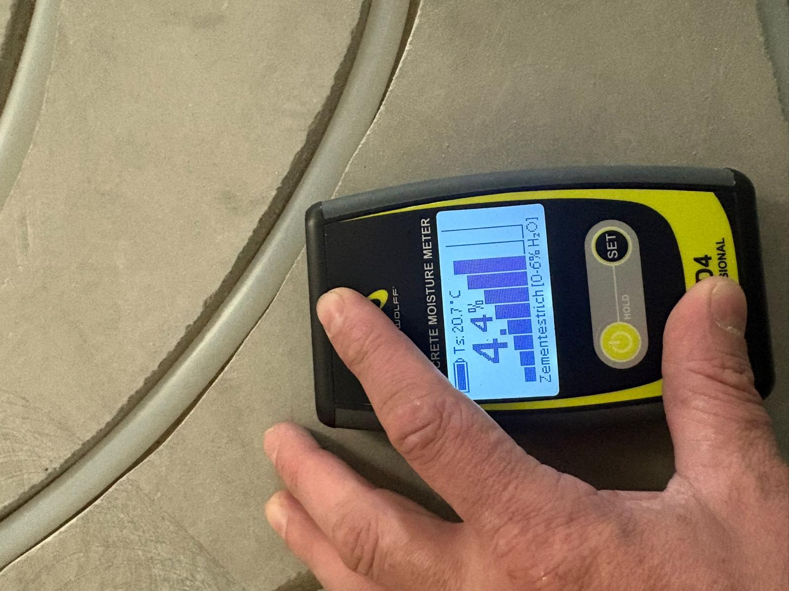 Vloerspecialist meet vocht in een dekvloer met een vochtmeter